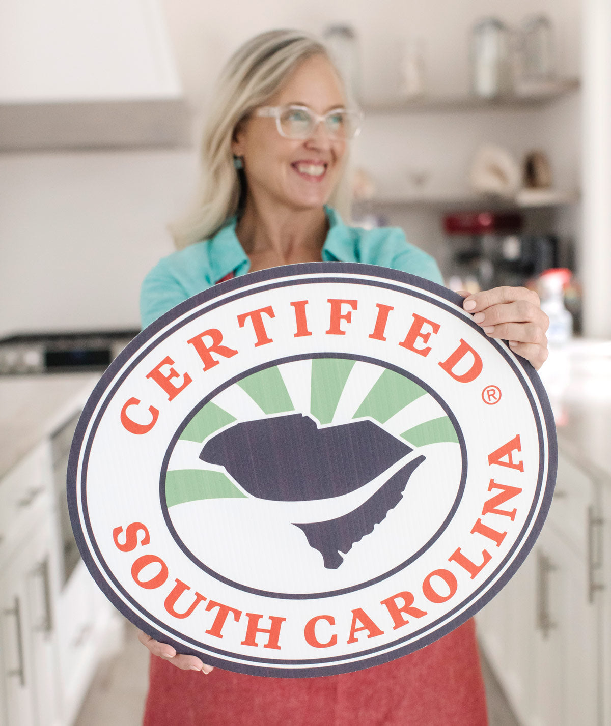 Minde Herbert, owner of Sea Island Organics, holds out a Certified South Carolina sign in her kitchen.