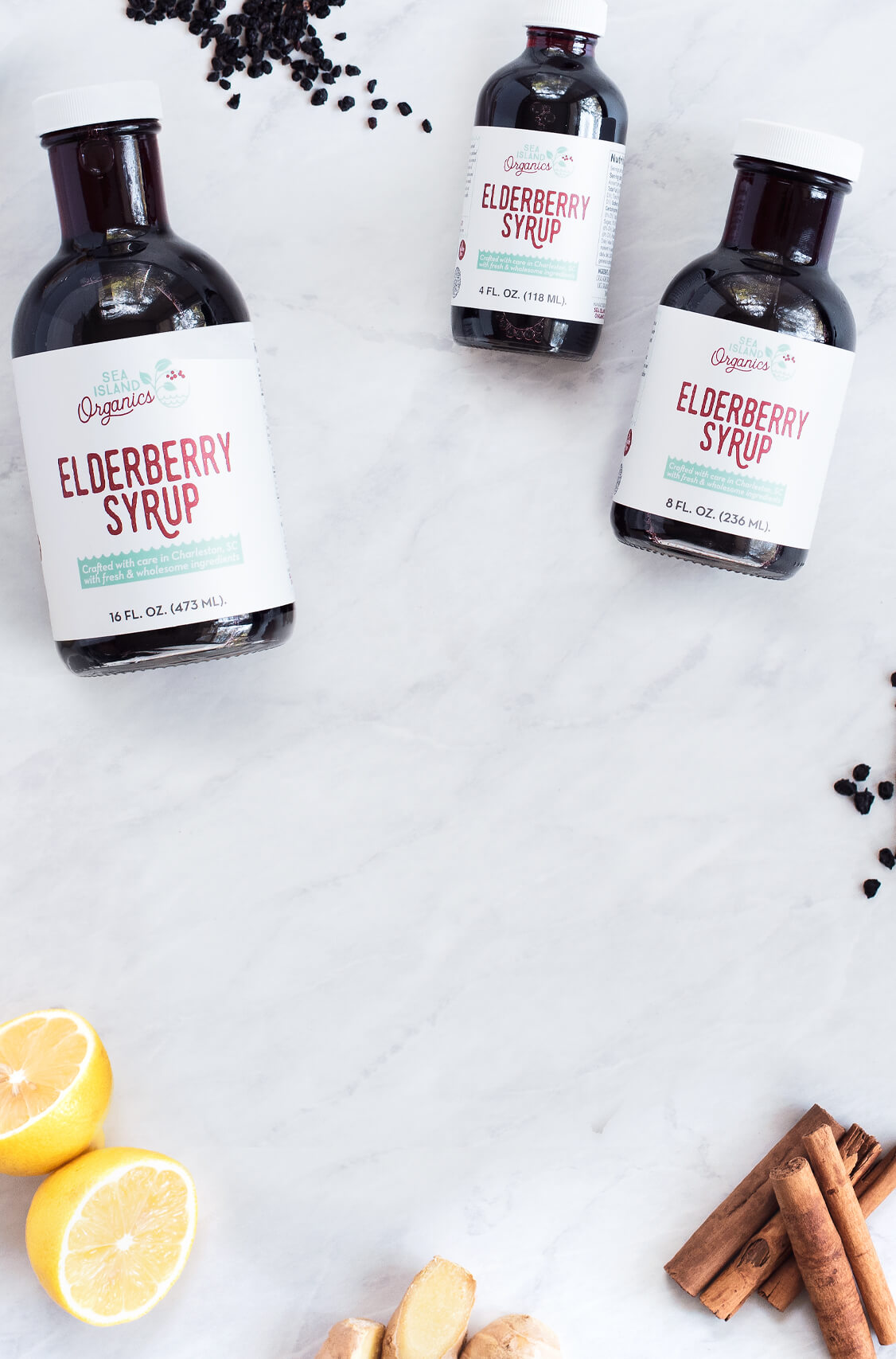 Handcrafted elderberry syrups & ingredients on a marble countertop.